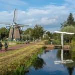 Nederlands landschap met een windmolen en fietsers